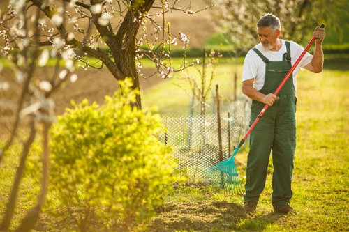 Workers using powered hedge trimmers with safety barriers